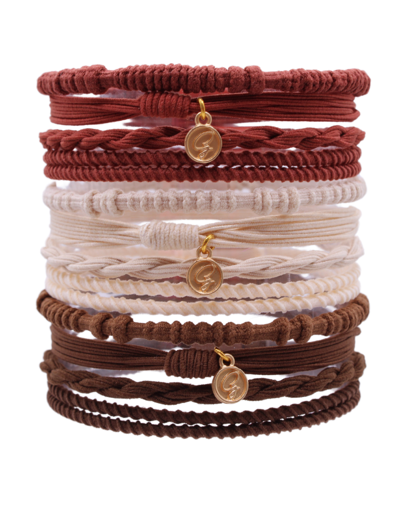 Stack of braided hair tie bracelets with gold charms in burgundy, cream, and brown