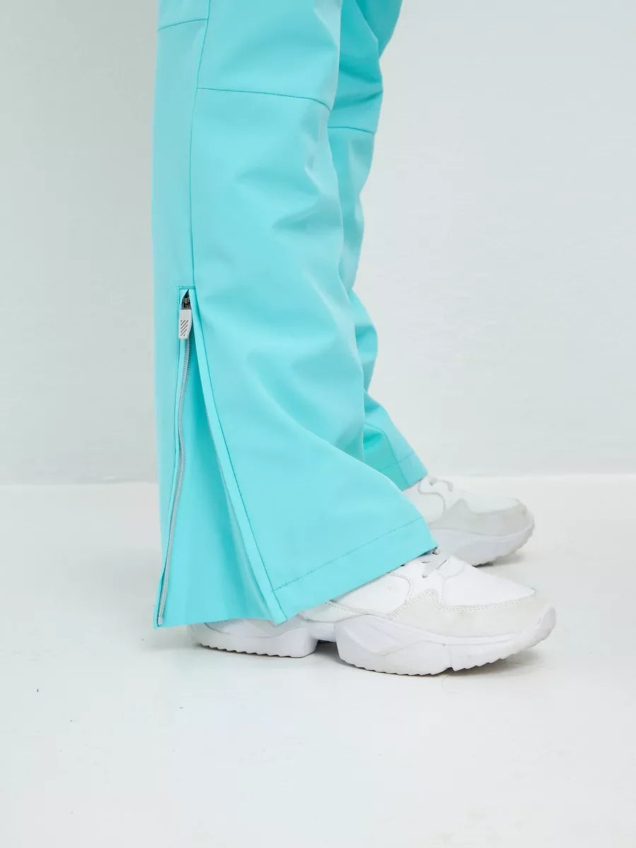 Mint insulated ski pants with ankle hem vent and overlay, worn with white boots.