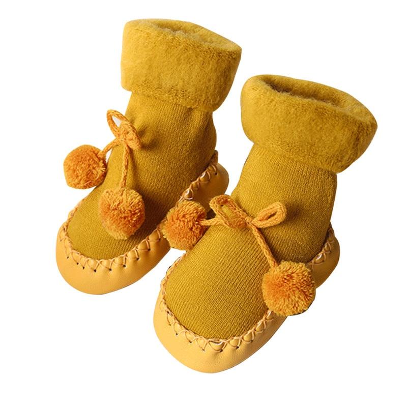 Pair of baby socks in yellow with pom-pom ties and stitched moccasin sole