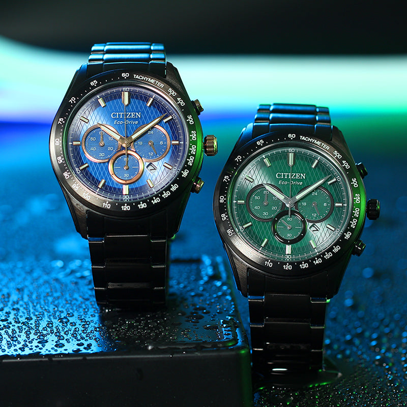 Two men's chronograph watches with blue and green dials and black metal bracelets.
