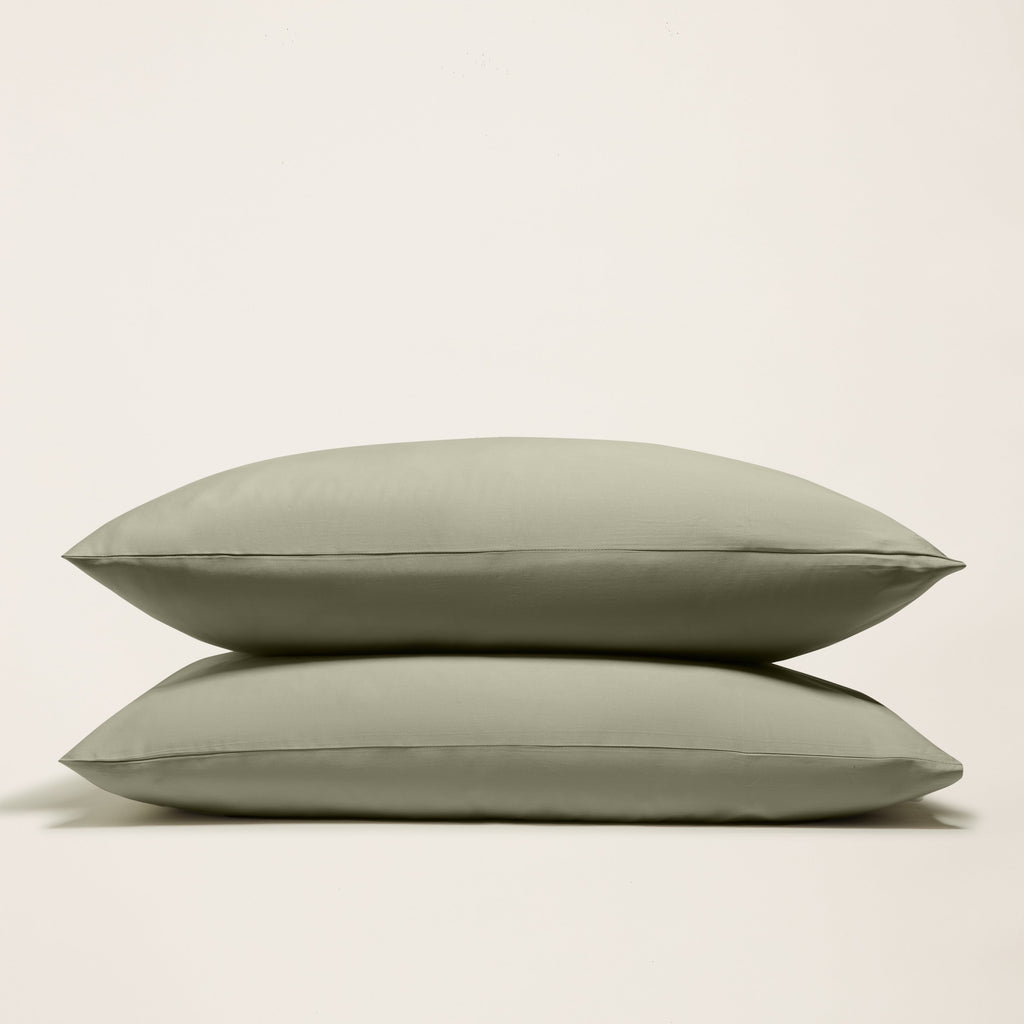 Olive green sateen sheet set with two folded pillowcases shown against light background