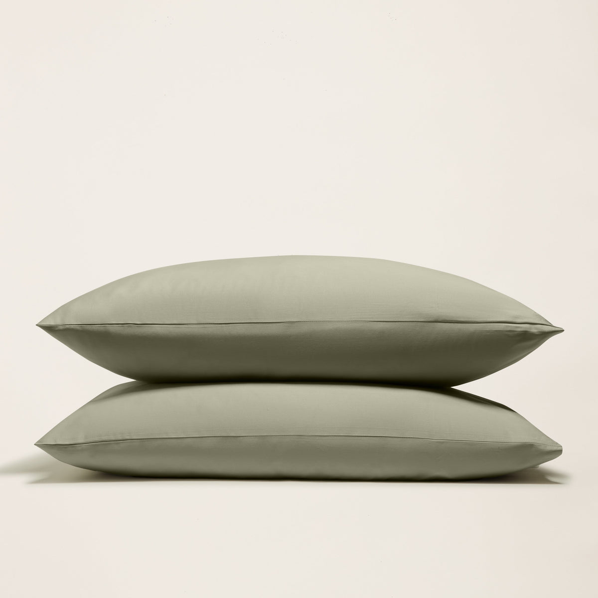 Olive green sateen sheet set with two folded pillowcases shown against light background