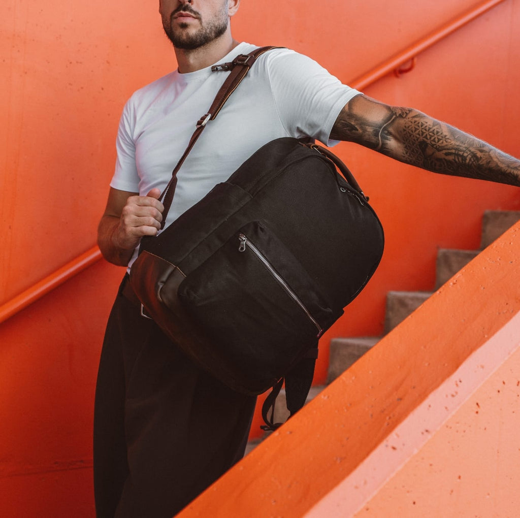 Black duffel-style backpack with side pocket and zip front panel