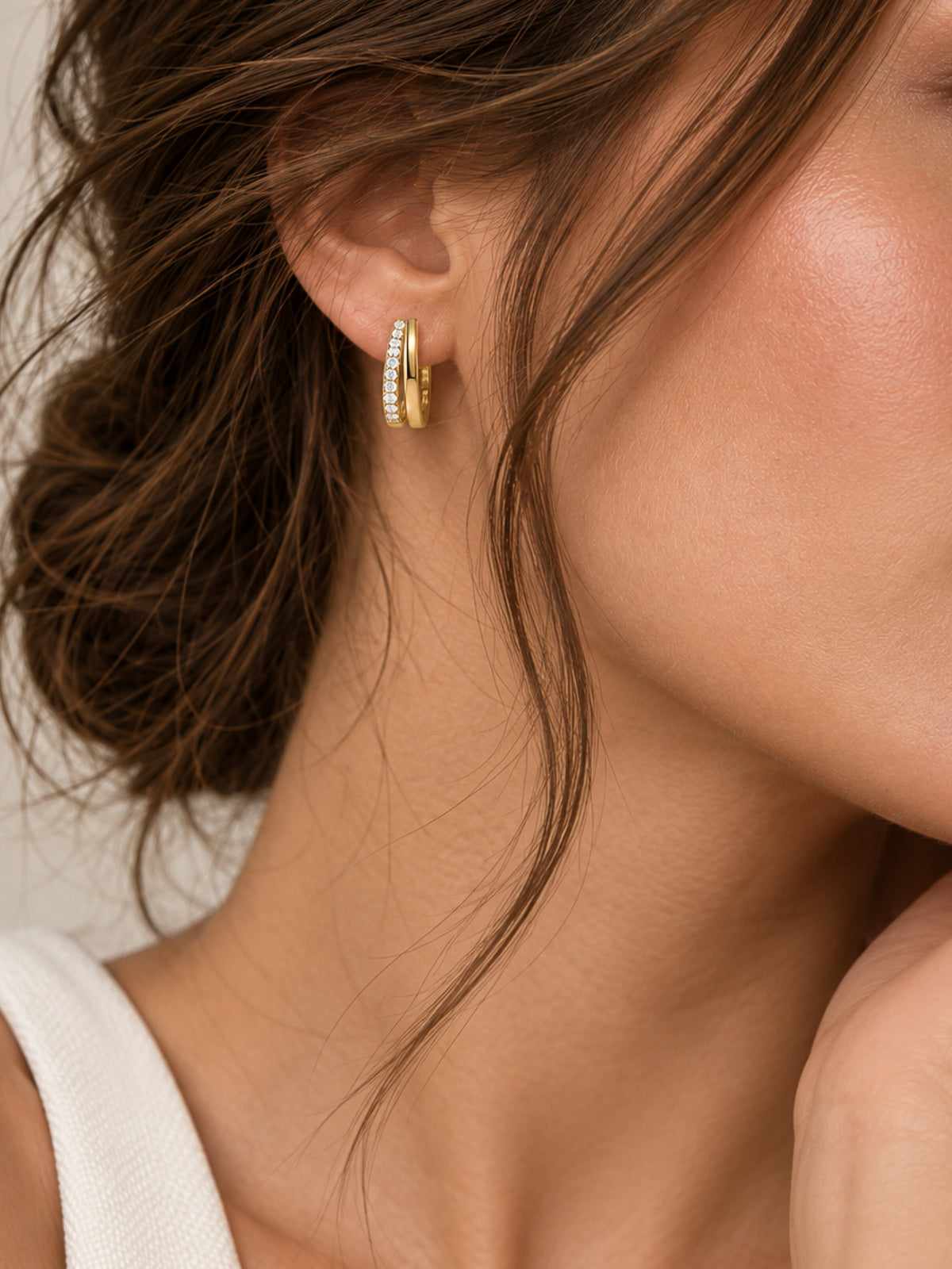 Gold-tone double hoop earrings with pave sparkle and small clear stones, worn