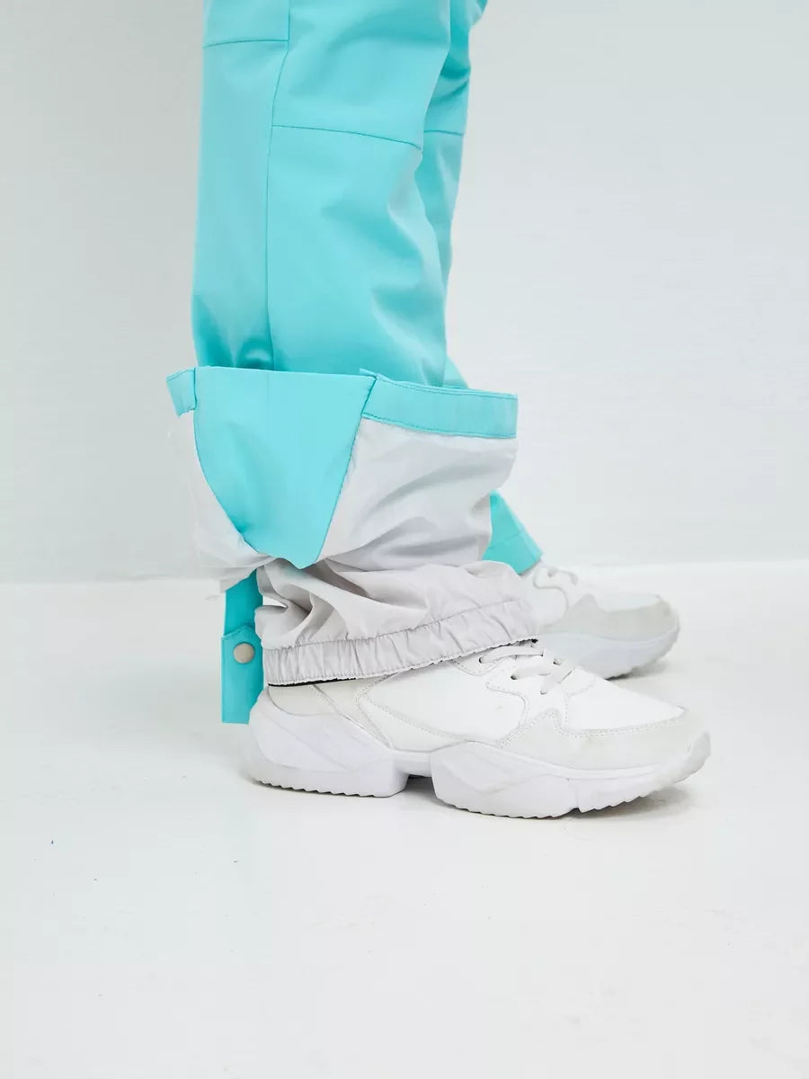 Mint ski pants with cuff and layered ankle fabric, worn with white boots.