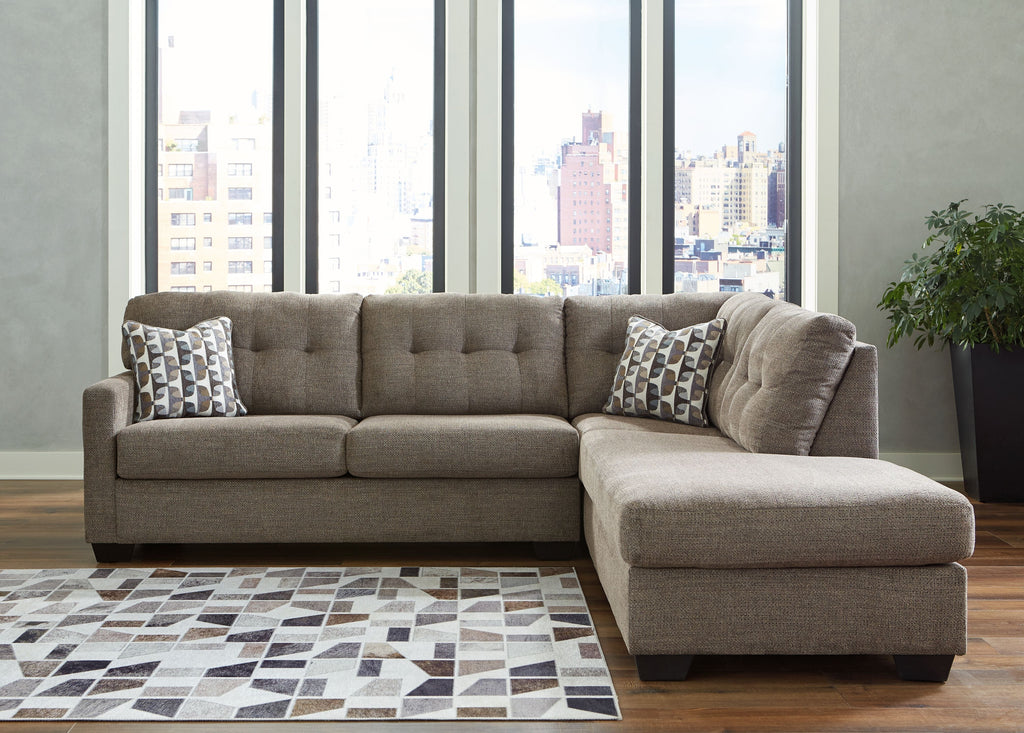 Light gray sectional sofa with corner chaise and tufted back cushions near windows