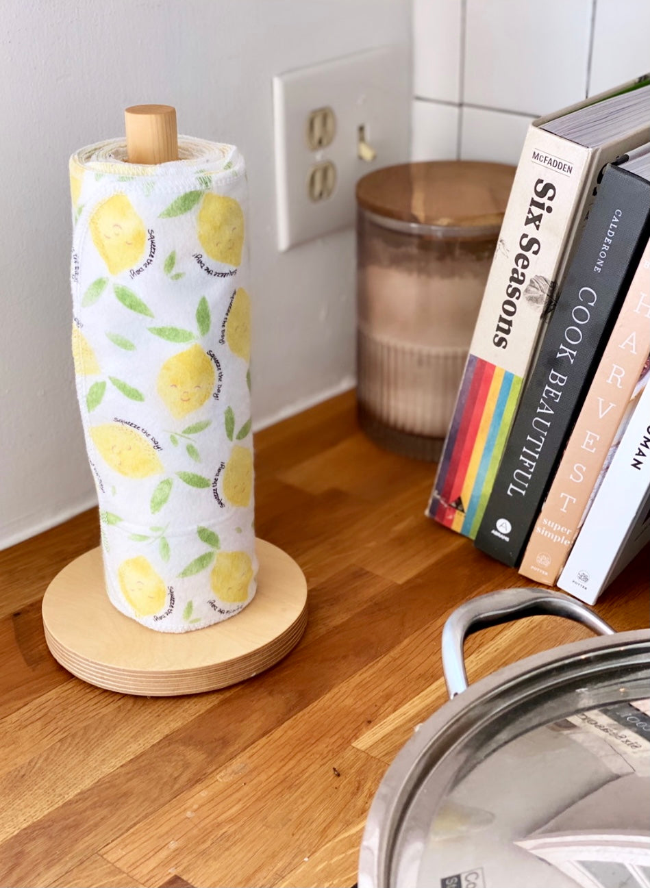 Reusable paper towel roll with yellow lemon leaf print on wooden holder