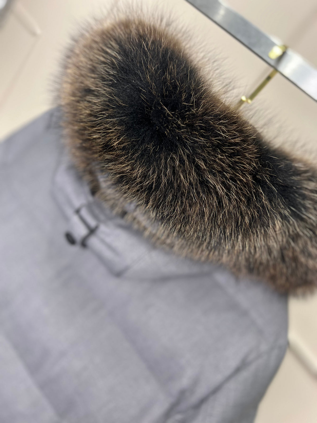 Faux fur hood trim on grey coat, close-up with soft brown-bronze texture