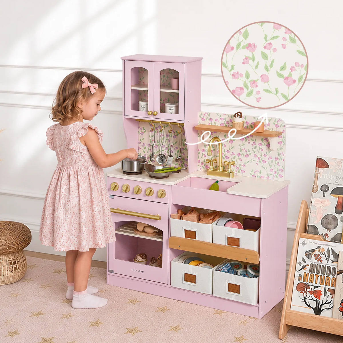 Light pink wooden play kitchen with open shelves, drawers, and toy accessories