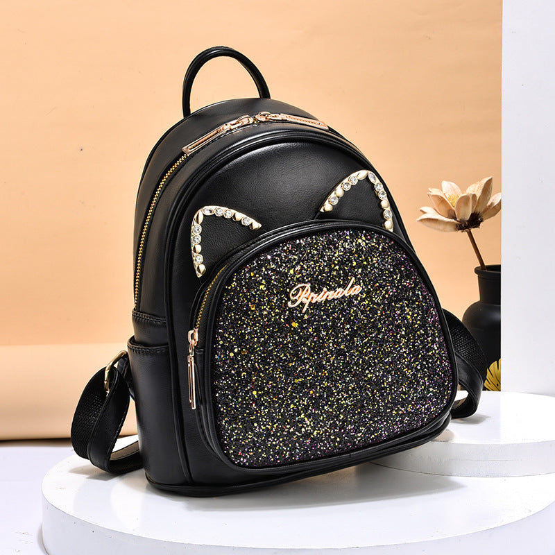 Black PU leather backpack with glitter front pocket, rhinestone trim, dual zippers, carry handle.