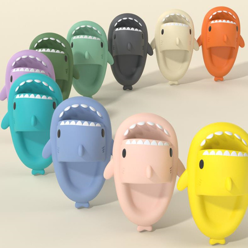 Assorted shark-shaped slide sandals in green, teal, gray, white, orange, and yellow
