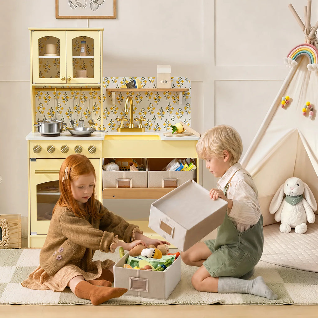 Cream wooden play kitchen with open storage shelves, sink and stovetop, toy cookware
