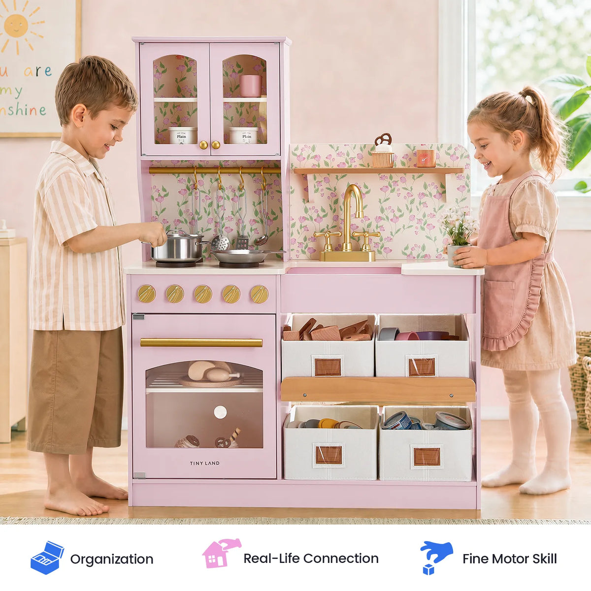Light pink kids wooden play kitchen with faucet, stove, and storage compartments