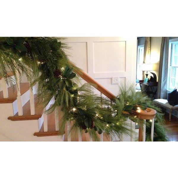 Faux pine garland draped with small warm lights and brown pinecones