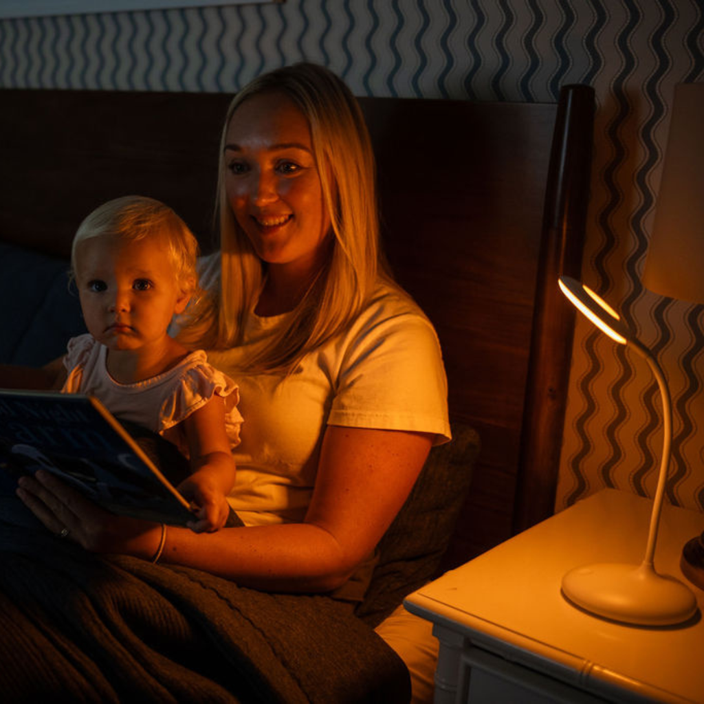 Bedside table lamp with curved stand and circular bulb opening, warm glow