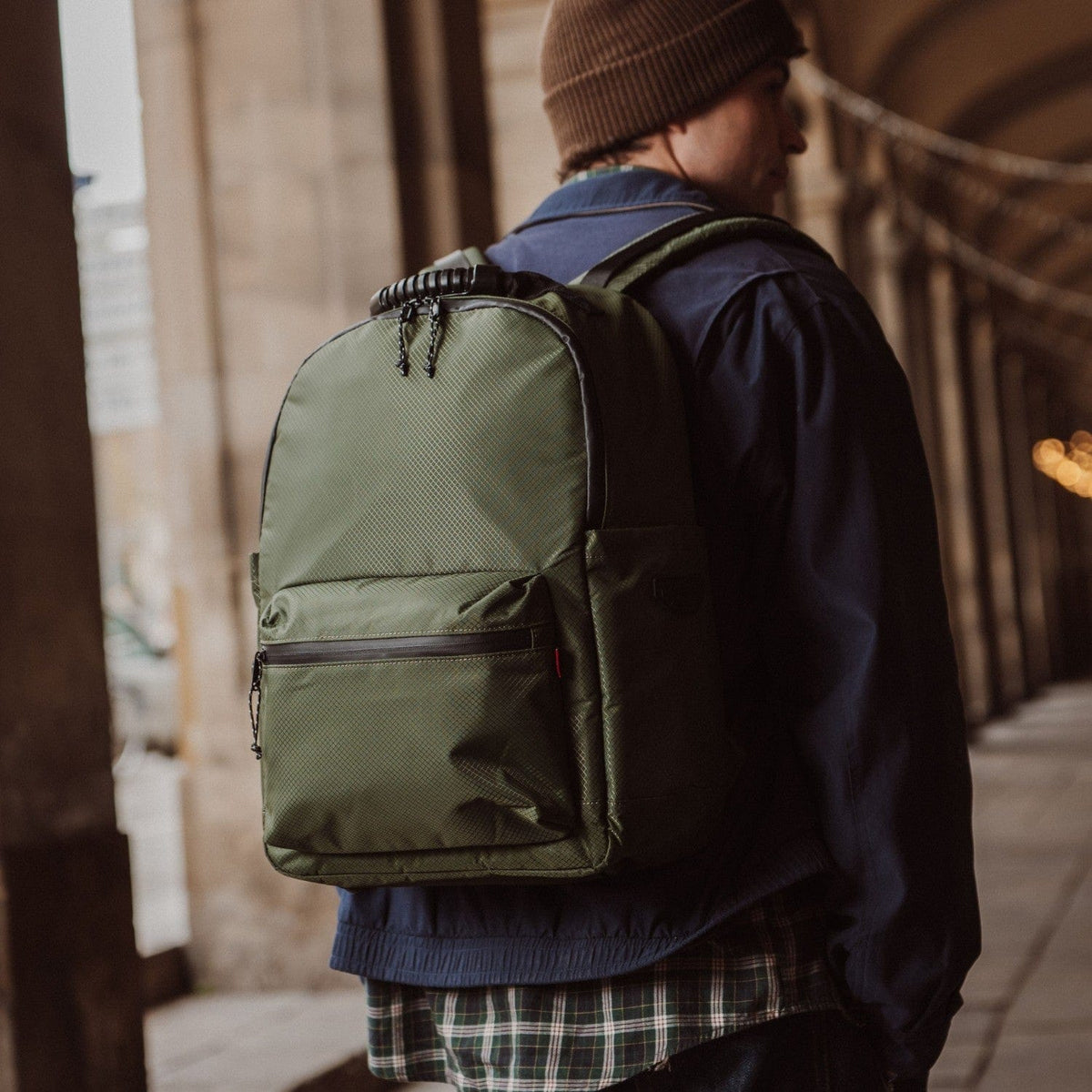 Green backpack with front pocket, zippered compartments, and chain zipper pulls.