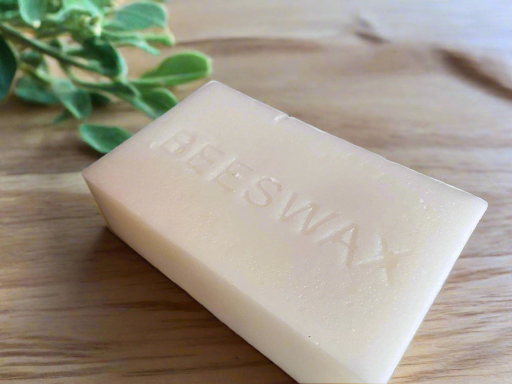 Beeswax block with embossed text on a light wood surface