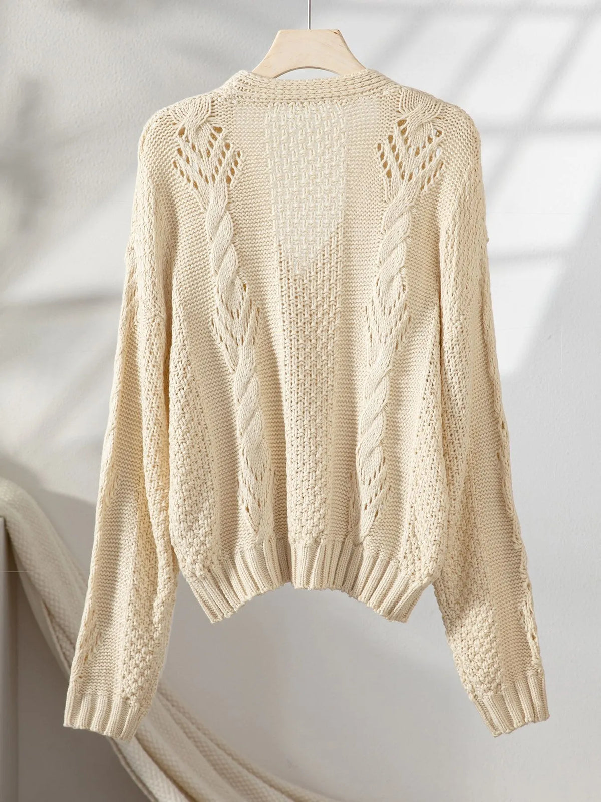Beige cropped cable-knit cardigan, back view with cable pattern and ribbed hem
