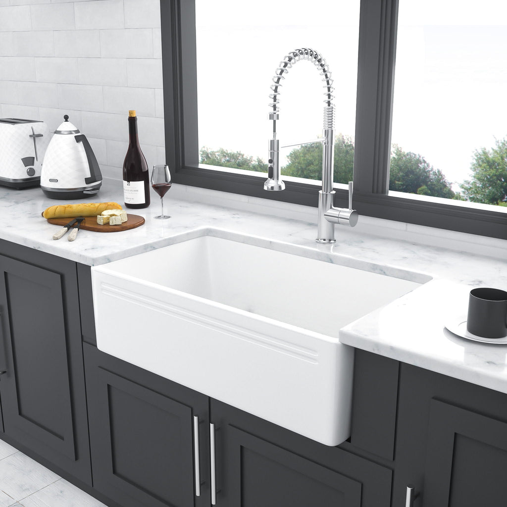 White ceramic single-bowl farmhouse apron front sink with curved basin and drain opening