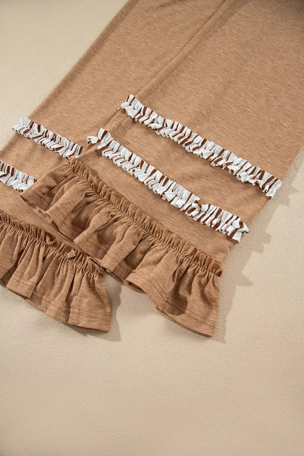 Camel drawstring pants with elastic waist and white ruffled trim along the hem