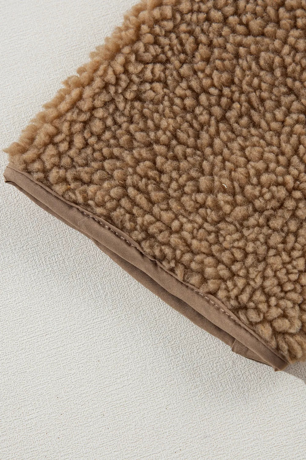 Khaki fleece hem edge with beige inner trim, close-up