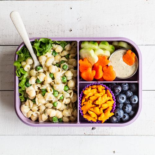 Snack lunch tray with cheddar crackers, pretzel pieces, and fruit in compartments