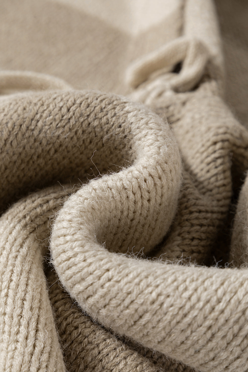 Close-up of beige chunky knit with ribbed trim and stitched texture