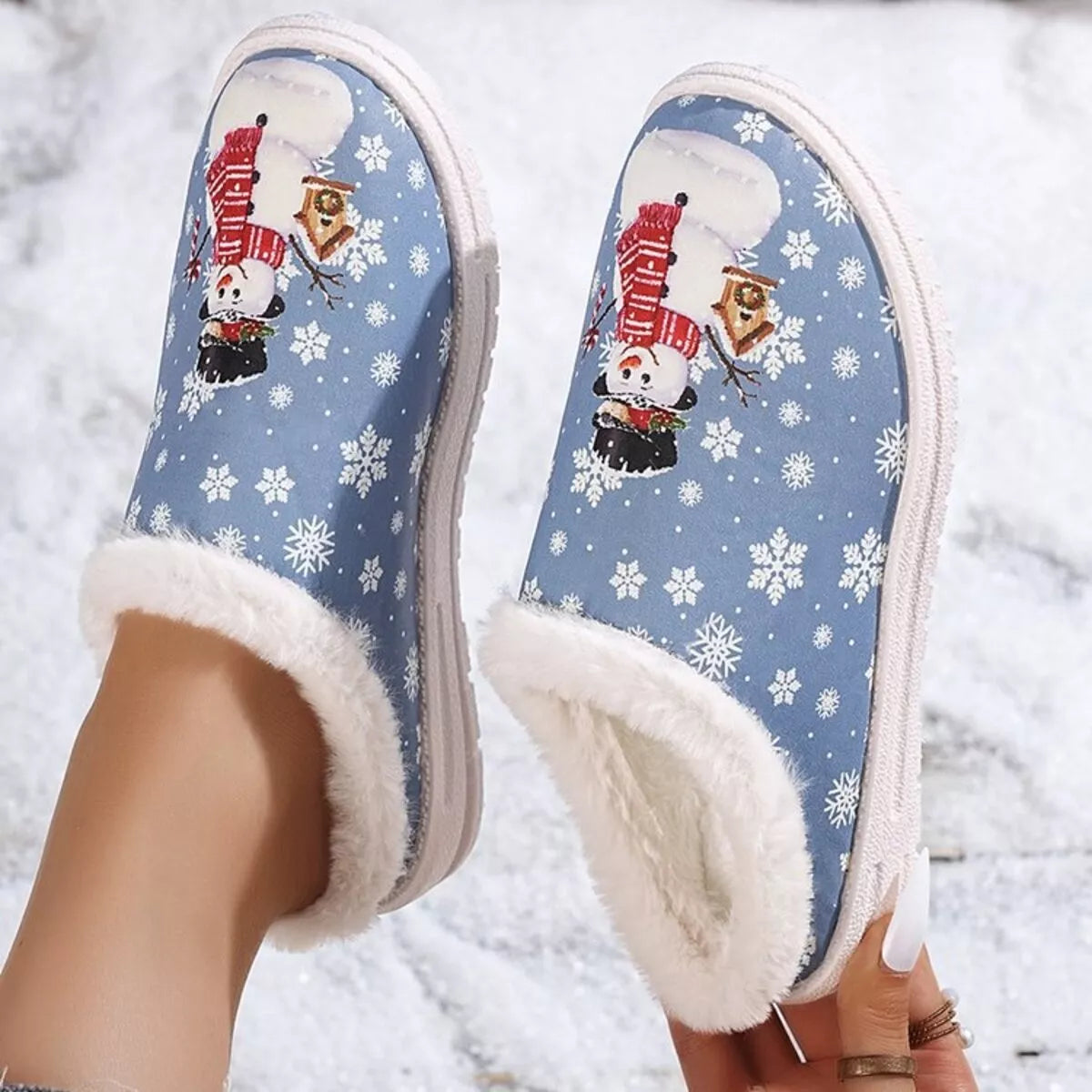 Blue plush-lined Christmas slippers featuring snowman and nutcracker holiday artwork