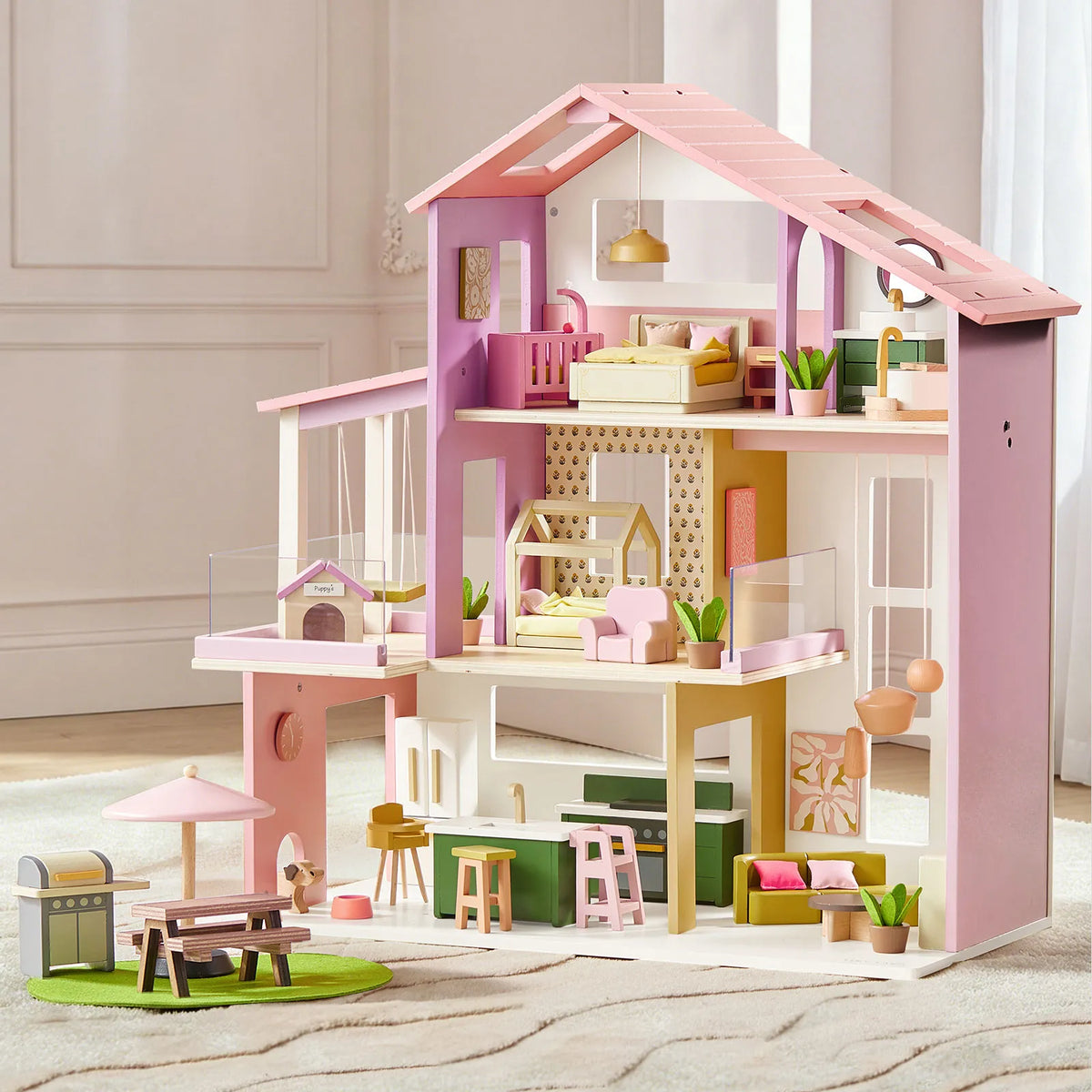 Pink and green dollhouse with multi-level rooms, balcony, and roof accents