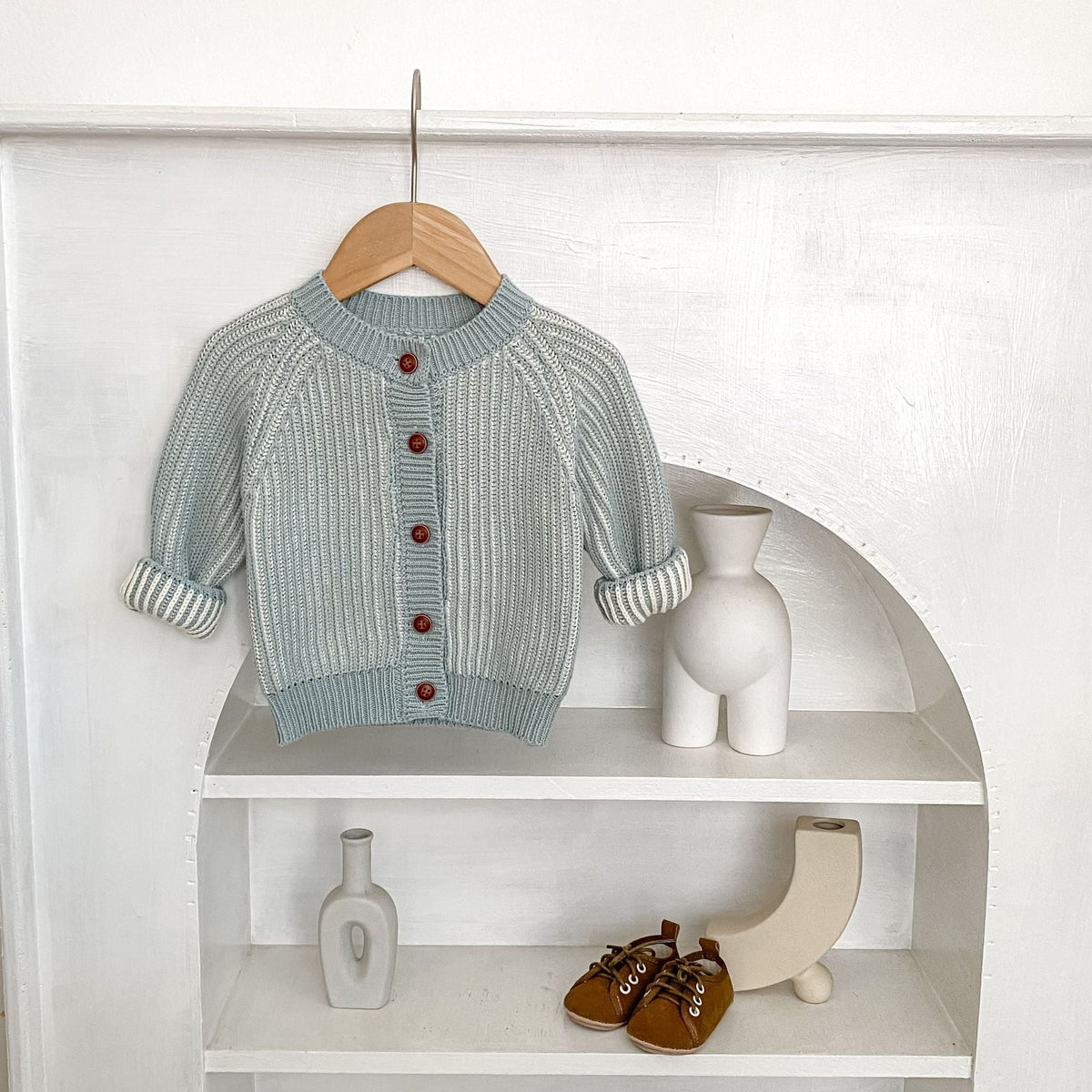 Infant light blue knit cardigan-style coat, round neck, long sleeves, red button placket