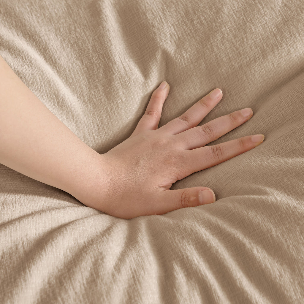 Close-up of beige sofa fabric with a hand pressing into the cushioned upholstery.