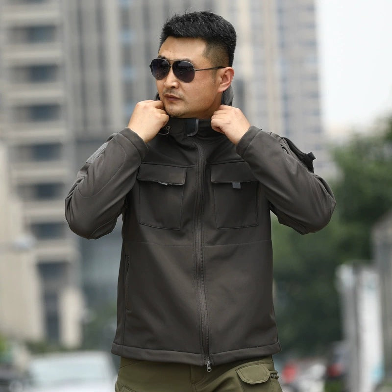Dark gray tactical shell jacket with stand collar and chest utility pocket tabs.