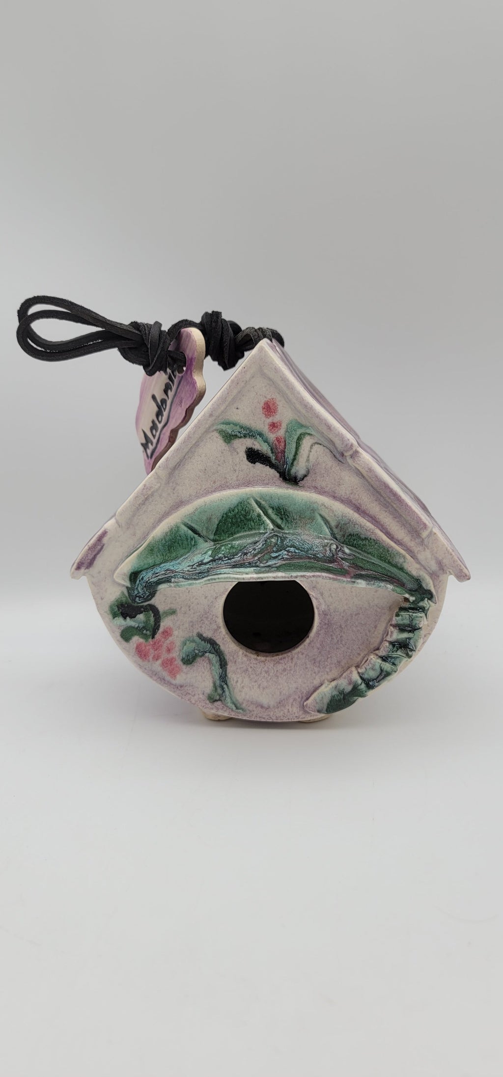 Clay bird house ornament with painted green bird and dark round entrance, hanging cord