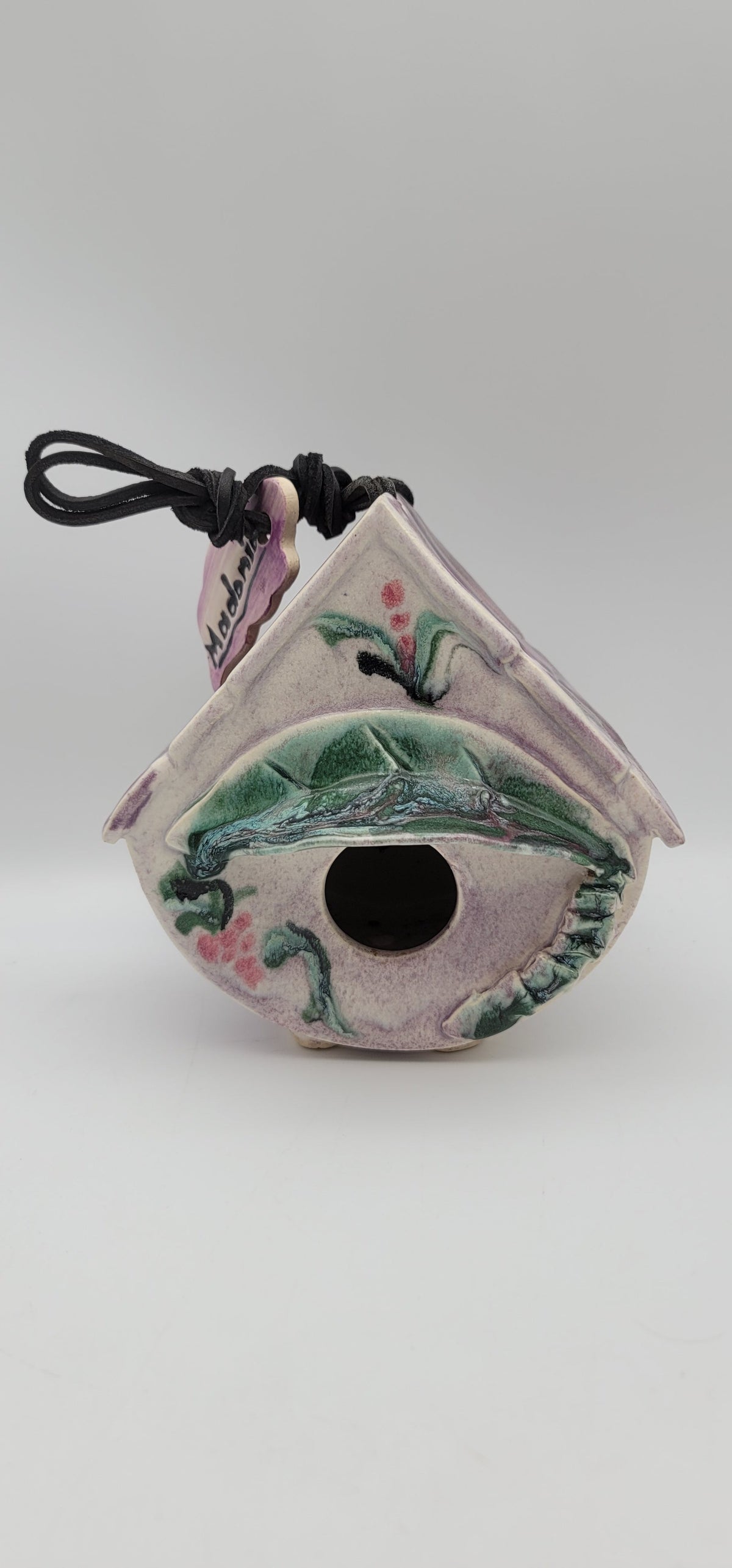 Clay bird house ornament with painted green bird and dark round entrance, hanging cord