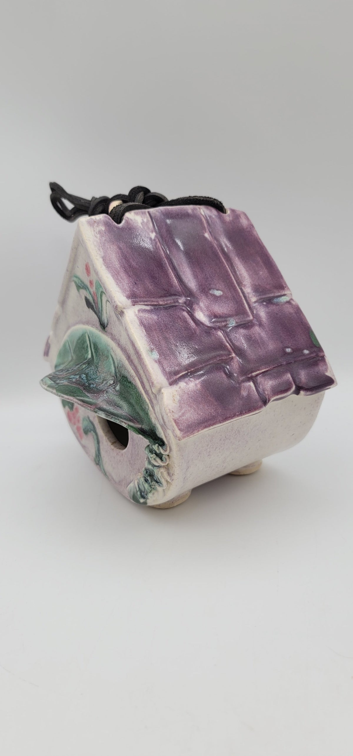 Clay bird house ornament with purple roof panels, painted green accents, side entrance, cord