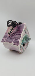 Vintage clay bird house with purple textured front, painted green accents, side entrance, cord
