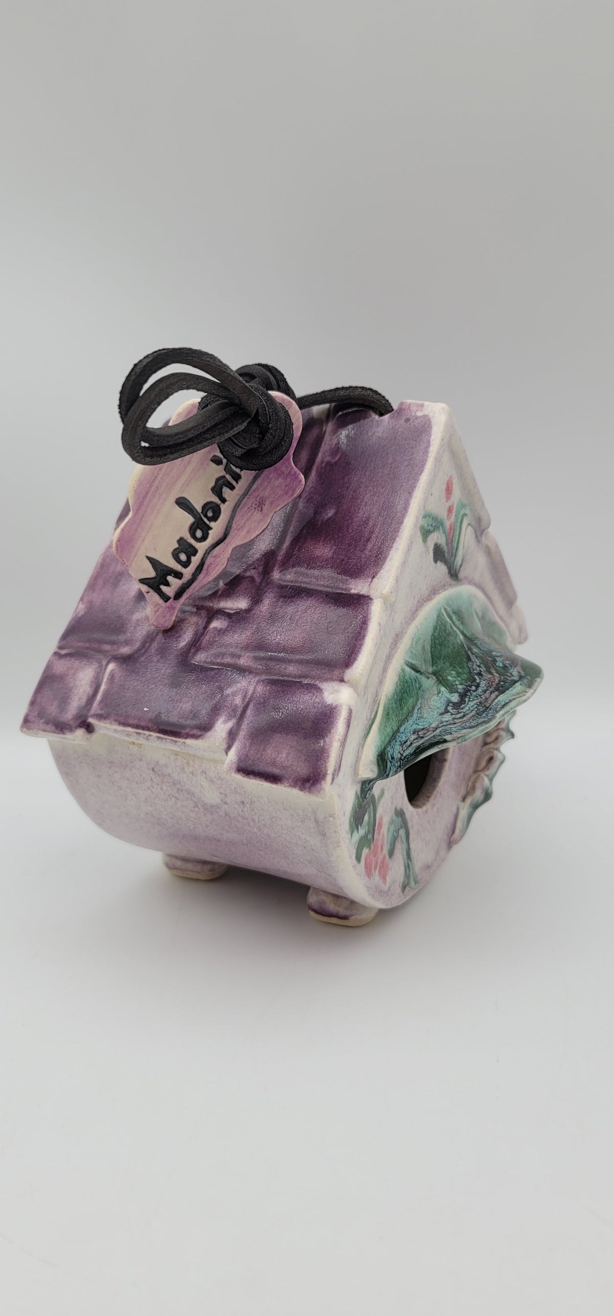 Vintage clay bird house with purple textured front, painted green accents, side entrance, cord