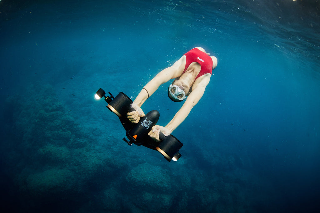 Underwater drone with cylindrical camera, held by scuba diver