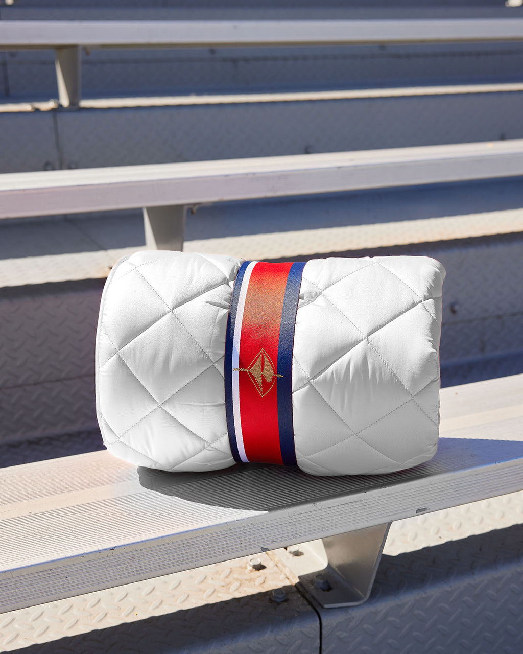 White quilted puffer blanket with red-and-blue bundle strap