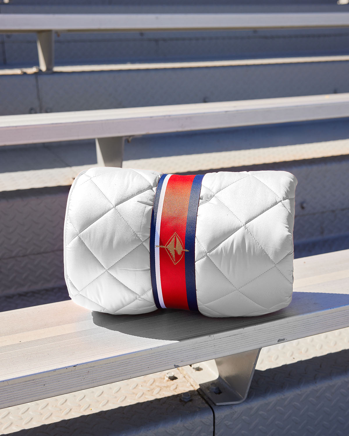 White quilted puffer blanket with red-and-blue bundle strap