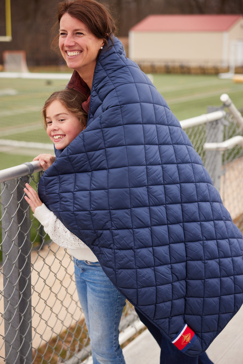 Navy quilted puffer blanket with pocket logo, held up