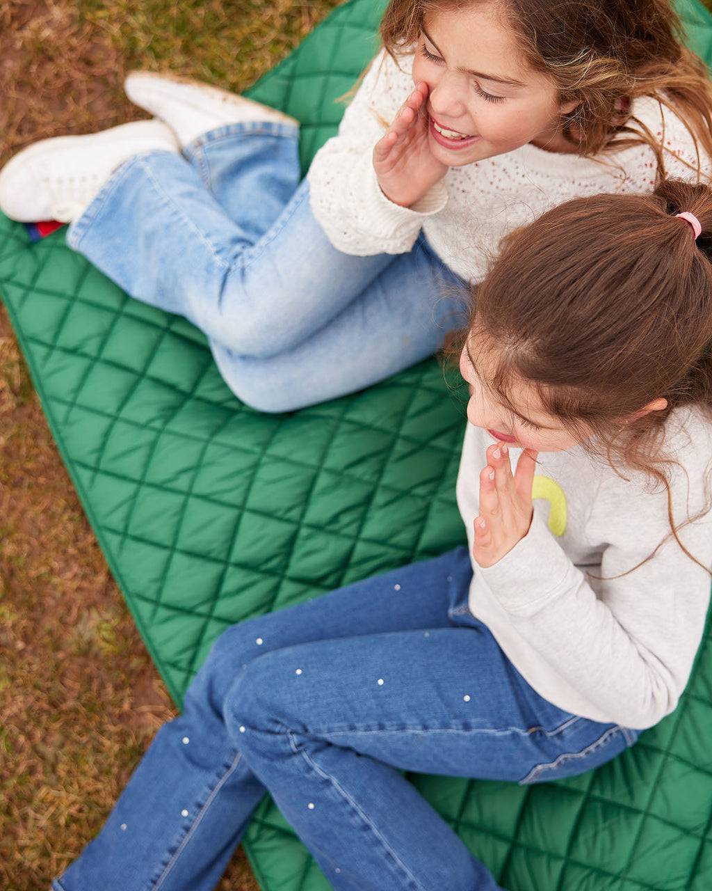 Green quilted puffer blanket with pocket edge, outdoors