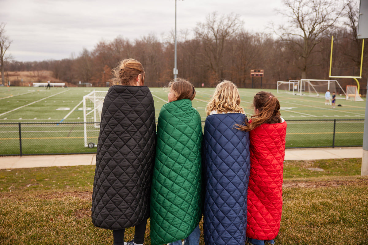 Waterproof puffer blanket with pockets, quilted panels in black, green, navy and red