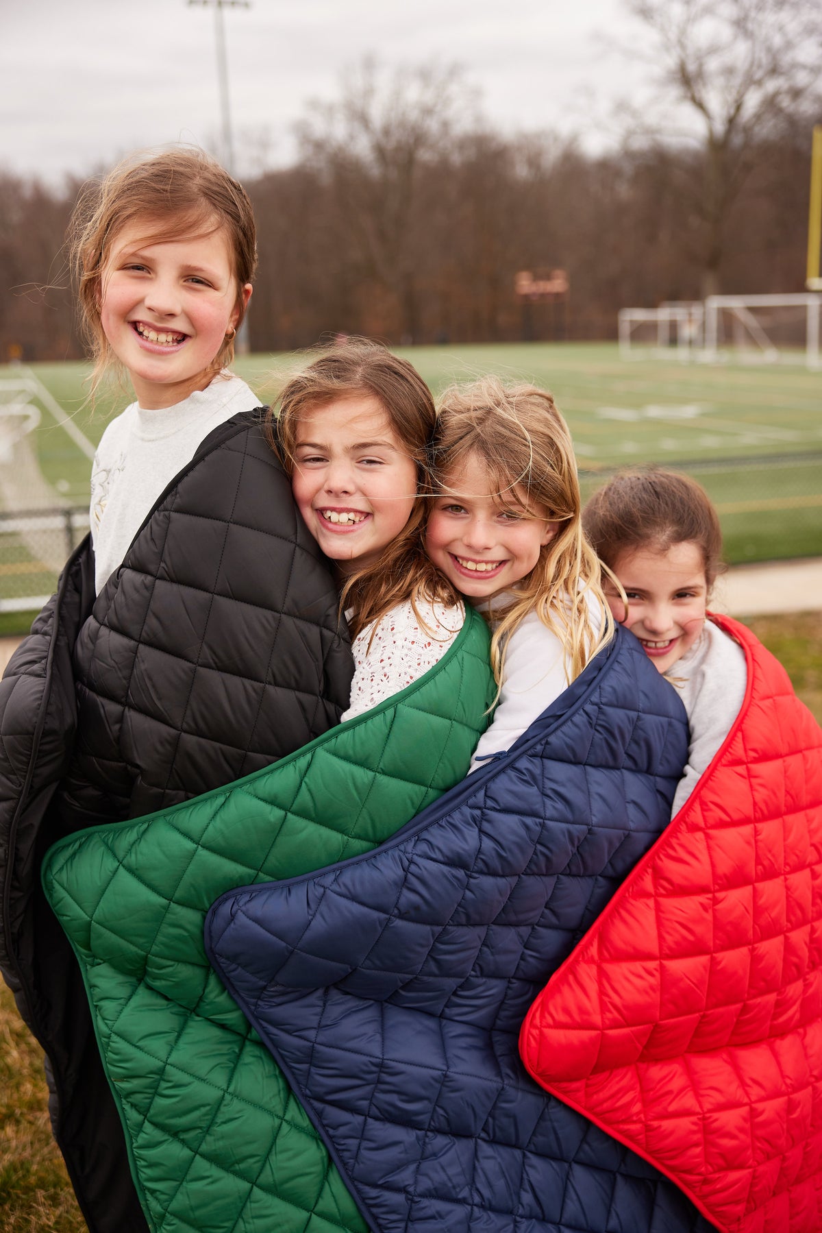 Quilted puffer blankets in green, navy, and red, overlapping