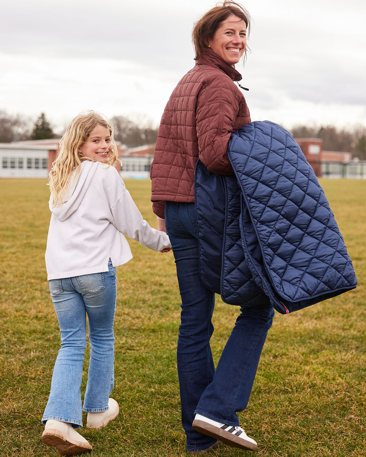 Dark blue quilted puffer blanket with pocket, draped outdoors