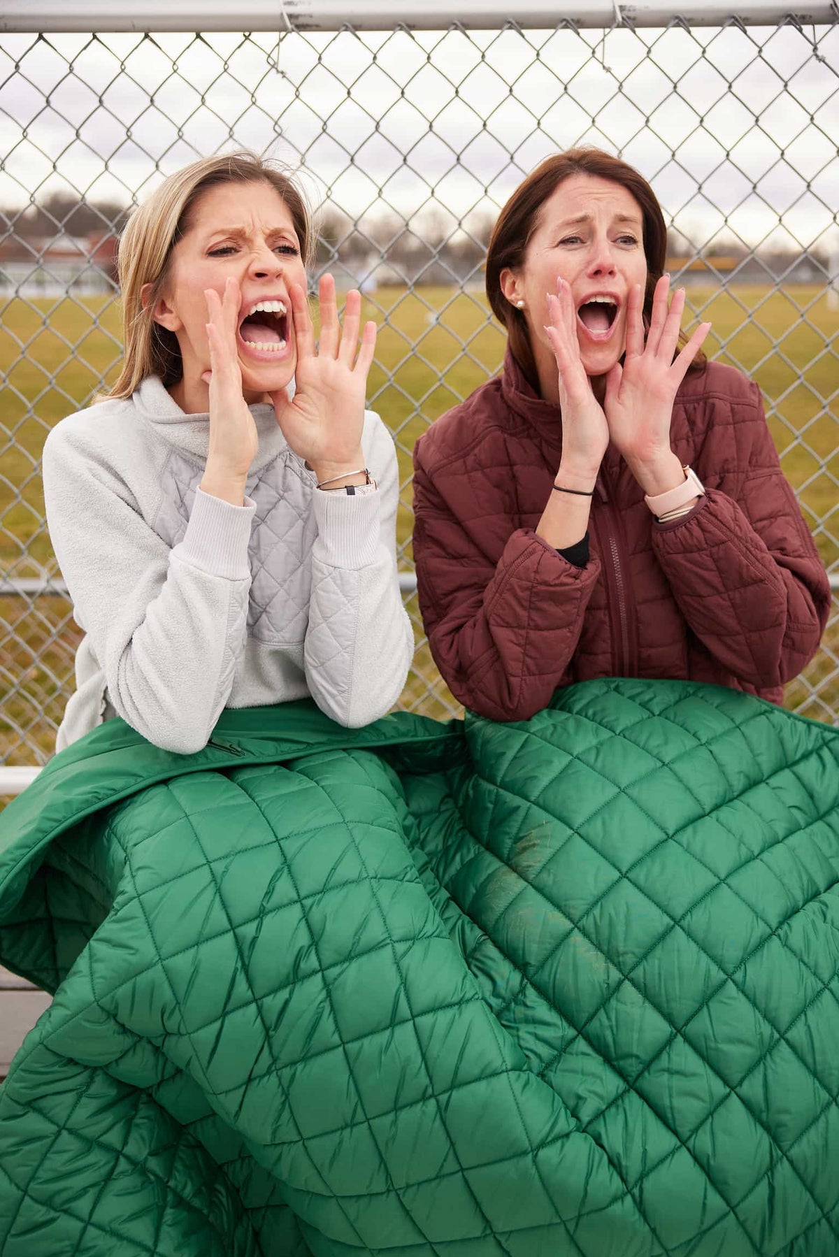 Waterproof puffer blanket with pockets, green quilted blanket covering the lap outdoors