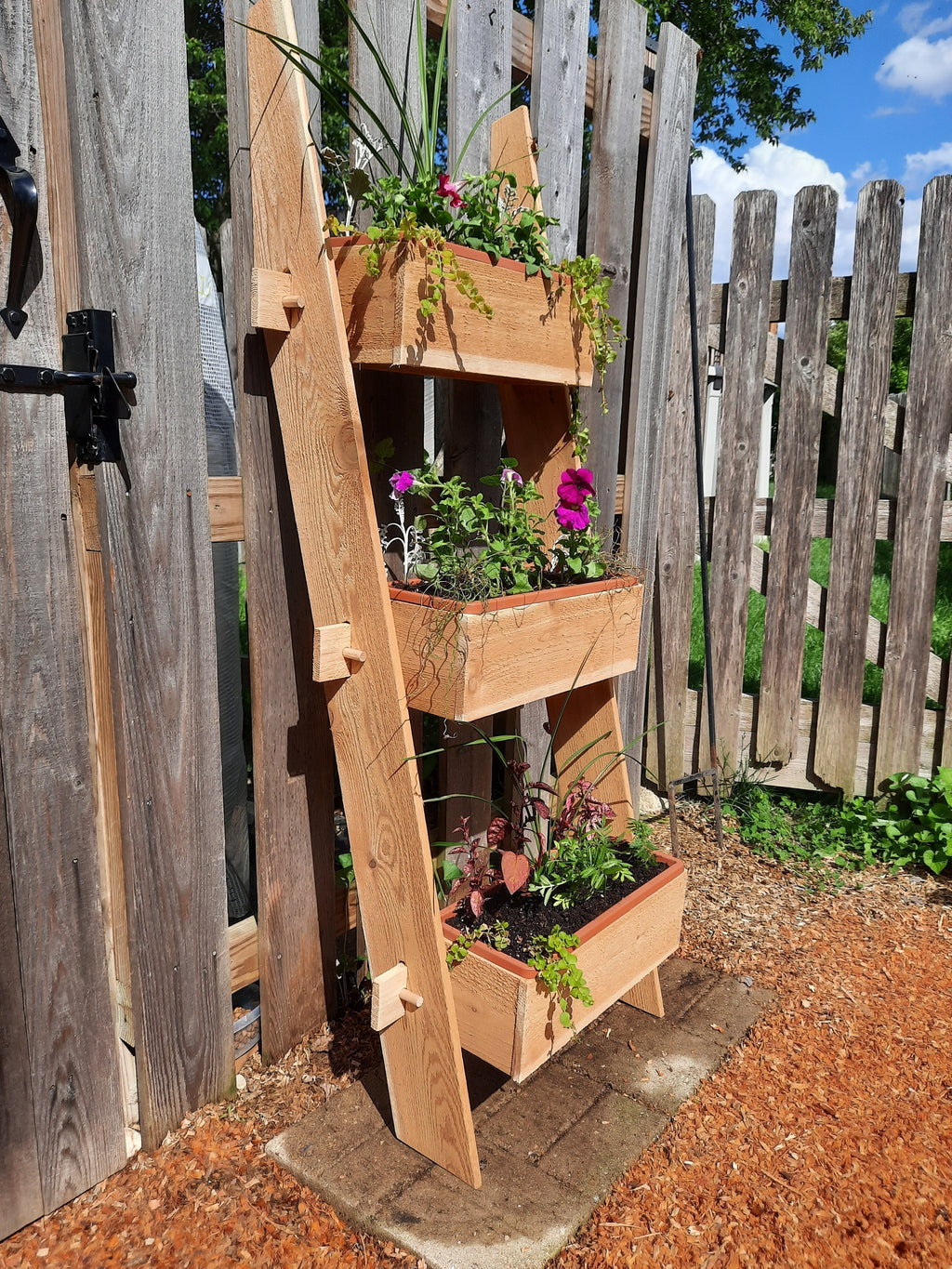 3-tier vertical cedar standing planter box with three wooden troughs and leafy plants
