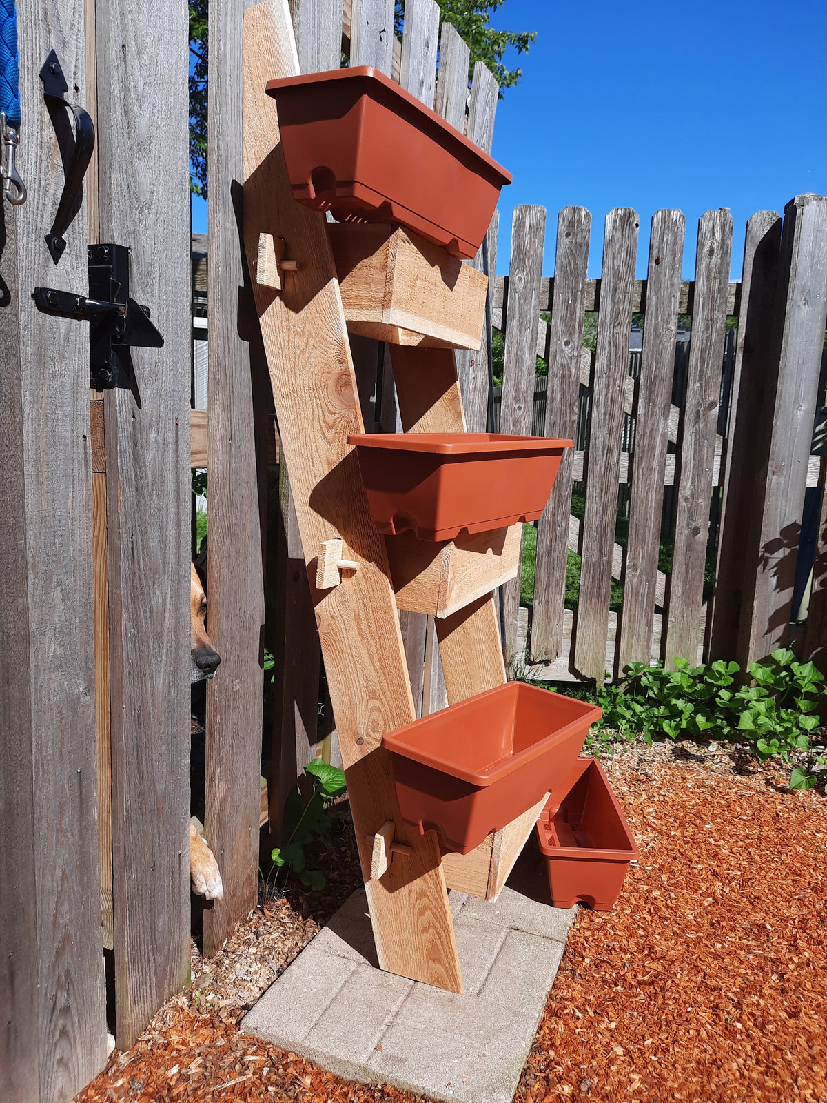 3-tier vertical cedar standing planter box with three orange planting containers on ladder frame