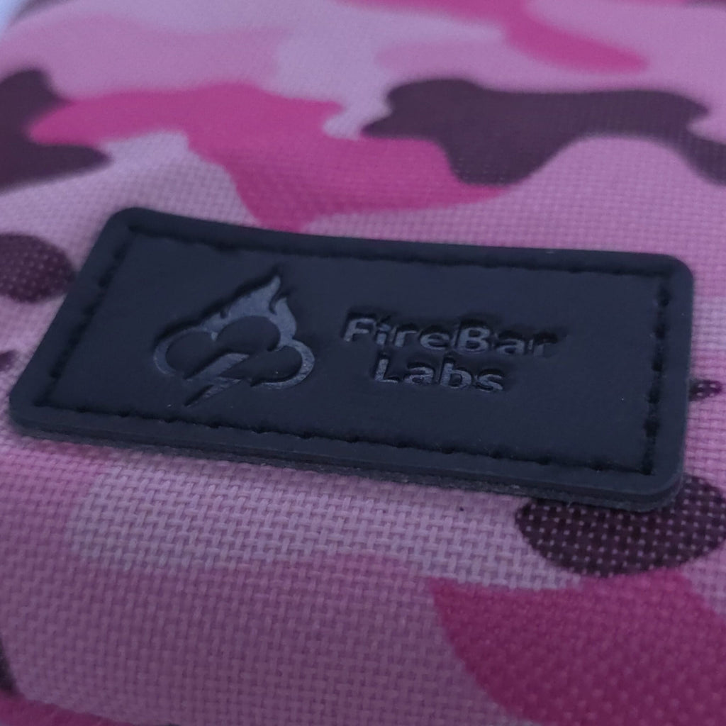 Pink camo crossbody bag close-up of black brand logo label