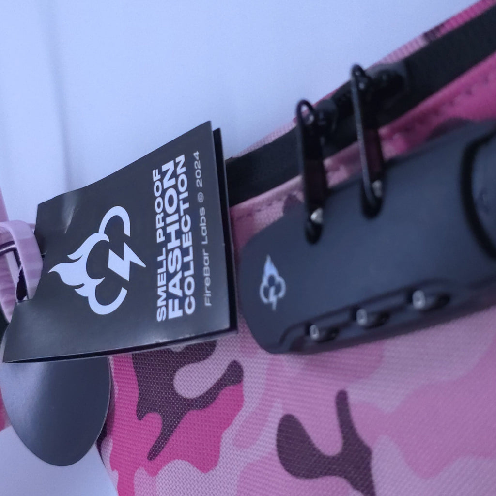 Pink camo crossbody bag with black smell-proof tag attached near strap